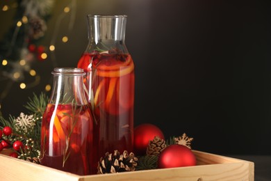 Glass bottles of aromatic punch drink and Christmas decor in tray, space for text