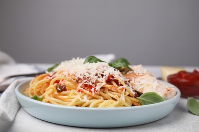 Delicious pasta with tomato sauce, basil and parmesan cheese on white table