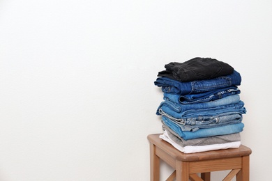 Photo of Stack of different jeans on table against white background. Space for text