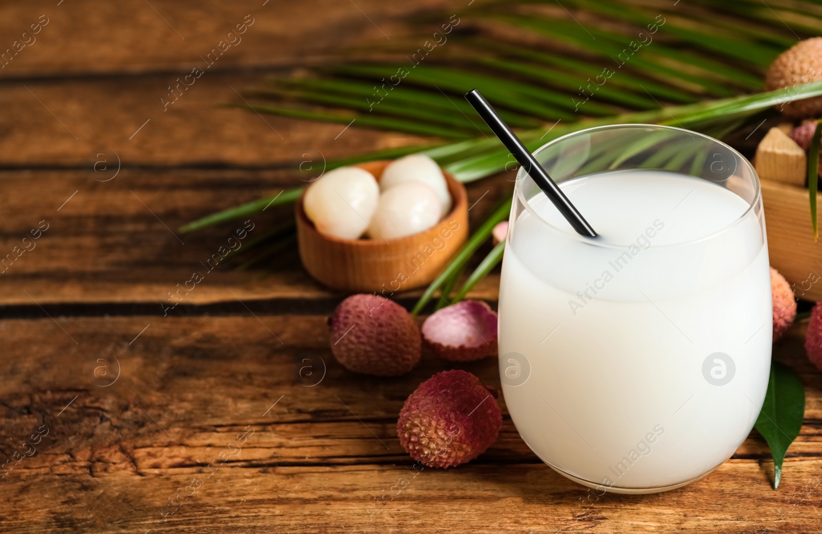 Photo of Lychee juice and fresh fruits on wooden table. Space for text