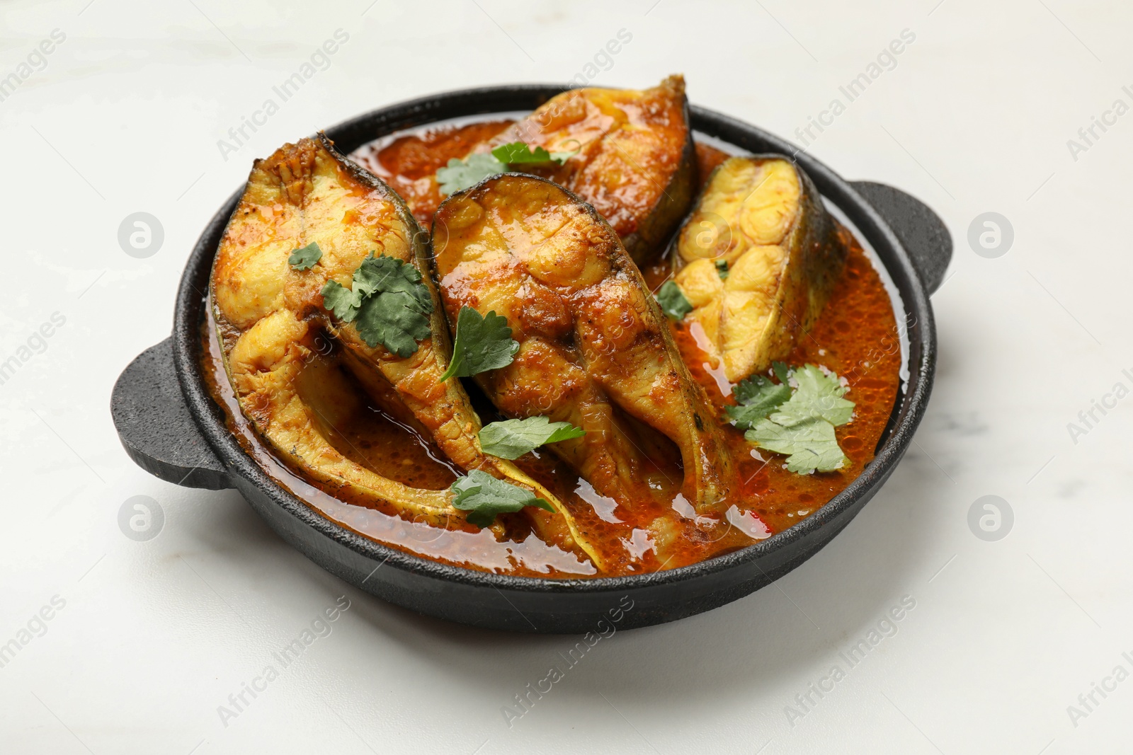 Photo of Tasty fish curry on white table, closeup. Indian cuisine