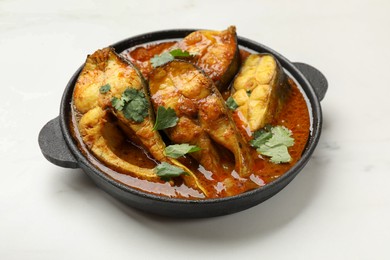 Photo of Tasty fish curry on white table, closeup. Indian cuisine
