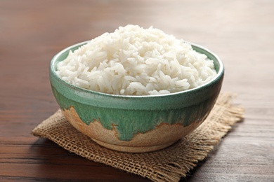Bowl of tasty cooked white rice on wooden table, closeup