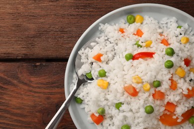 Photo of Delicious rice with vegetables on wooden table, top view. Space for text