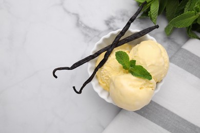 Photo of Delicious ice cream, mint and vanilla pods on white marble table, flat lay. Space for text