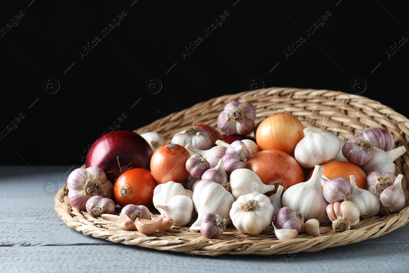 Photo of Fresh raw garlic and onions on gray wooden table against black background