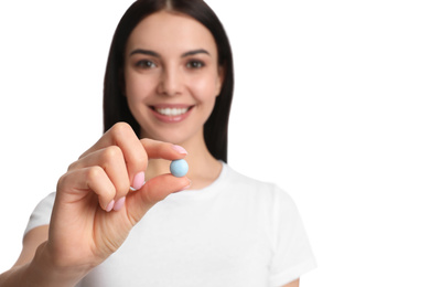 Young woman with vitamin pill on white background