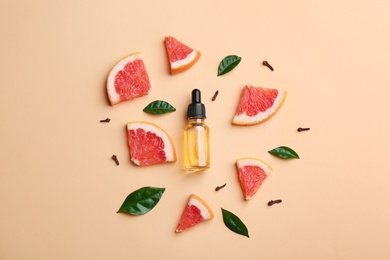 Photo of Flat lay composition with grapefruit slices and bottle of essential oil on color background