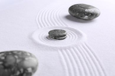 Photo of Zen concept. Stones and pattern on white sand, closeup