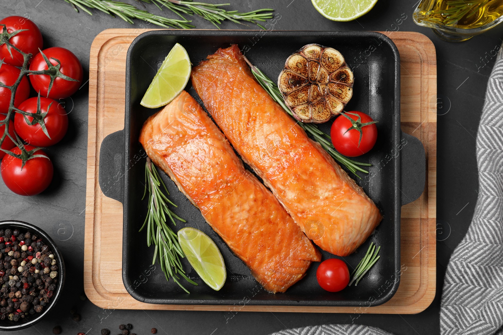 Photo of Delicious roasted fish served on black table, flat lay