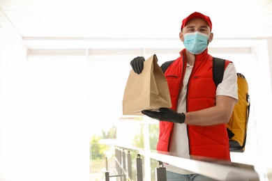 Courier in protective mask and gloves with order indoors. Restaurant delivery service during coronavirus quarantine