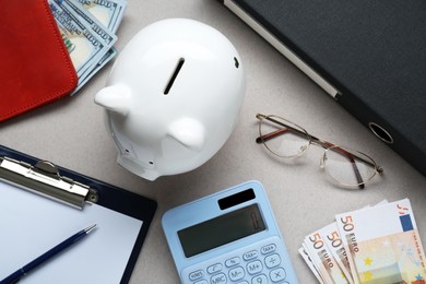 Flat lay composition with piggy bank, glasses and banknotes on grey background