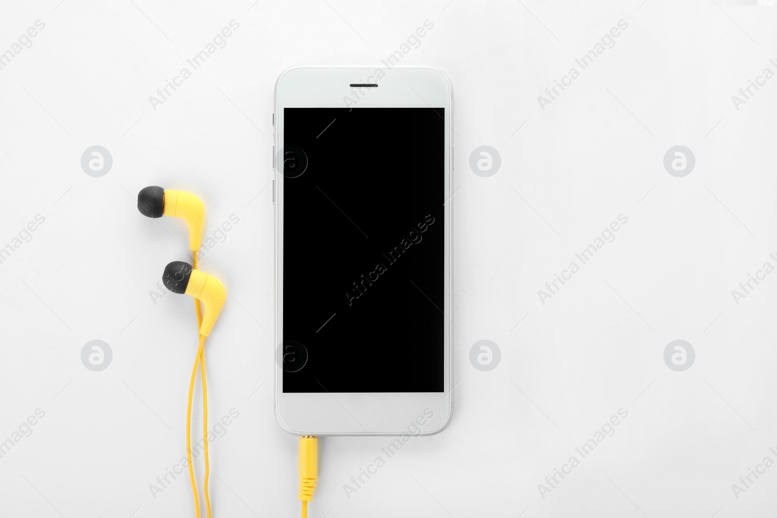 Photo of Smartphone with blank screen and headphones on white background, top view