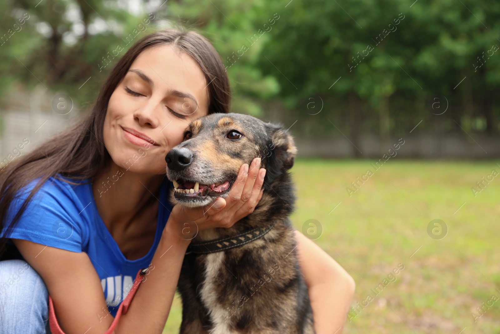 Photo of Female volunteer with homeless dog at animal shelter outdoors