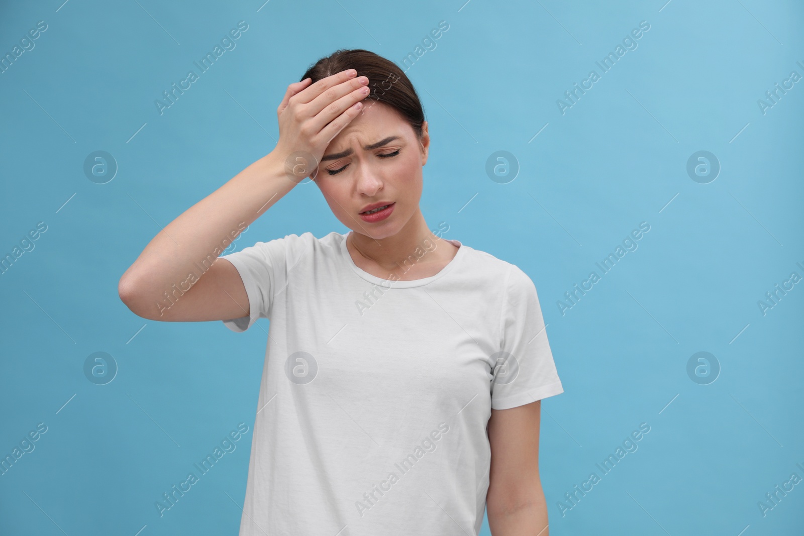 Photo of Woman suffering from headache on light blue background. Cold symptoms