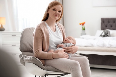 Photo of Mother with her little baby sitting in armchair at home