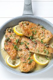 Delicious chicken piccata on white wooden table, top view