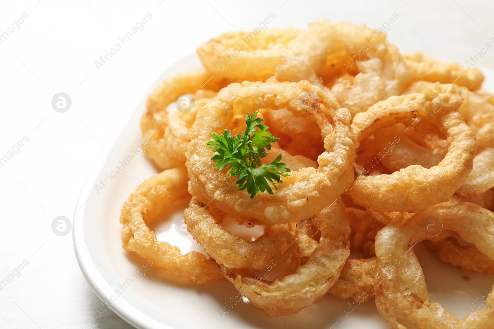 Photo of Homemade crunchy fried onion rings in plate on white background, closeup