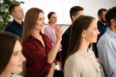 Photo of Woman raising hand to ask question at business training indoors