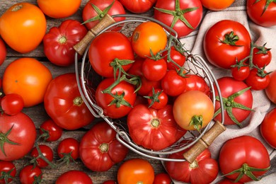 Many different ripe tomatoes on wooden table, flat lay