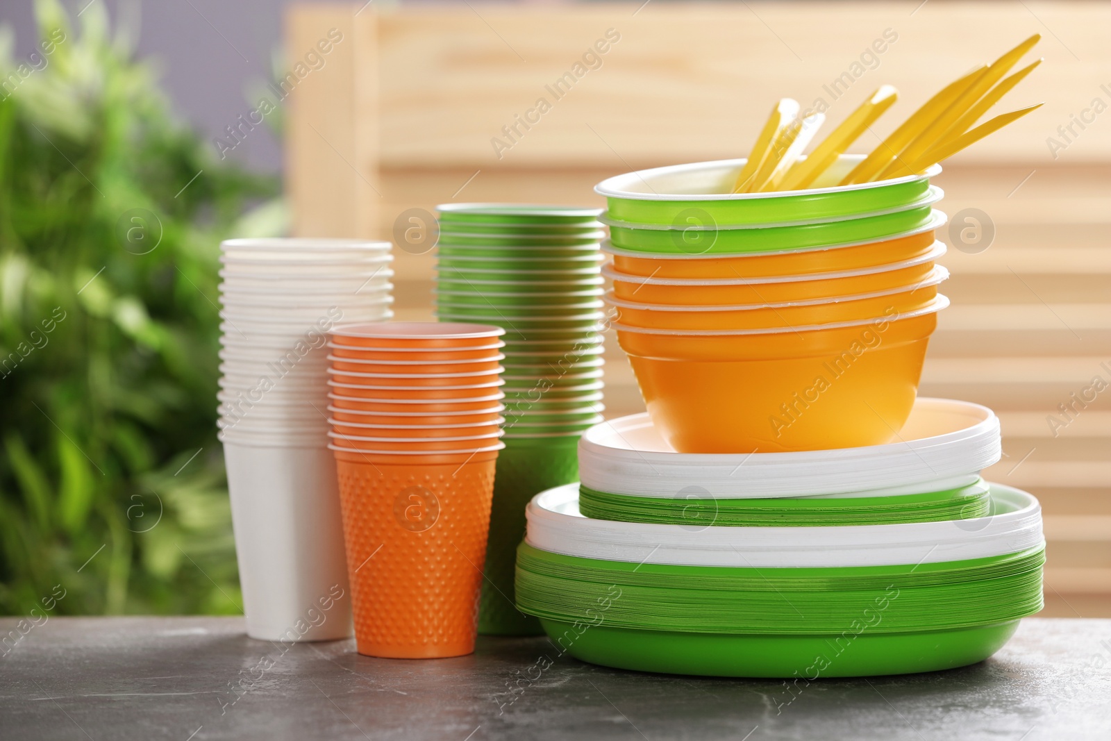 Photo of New plastic dishware on table against blurred background. Table setting