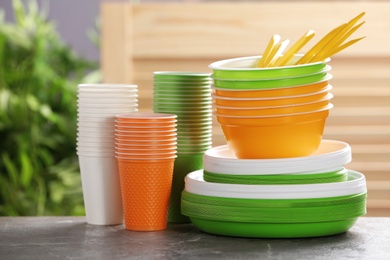 Photo of New plastic dishware on table against blurred background. Table setting