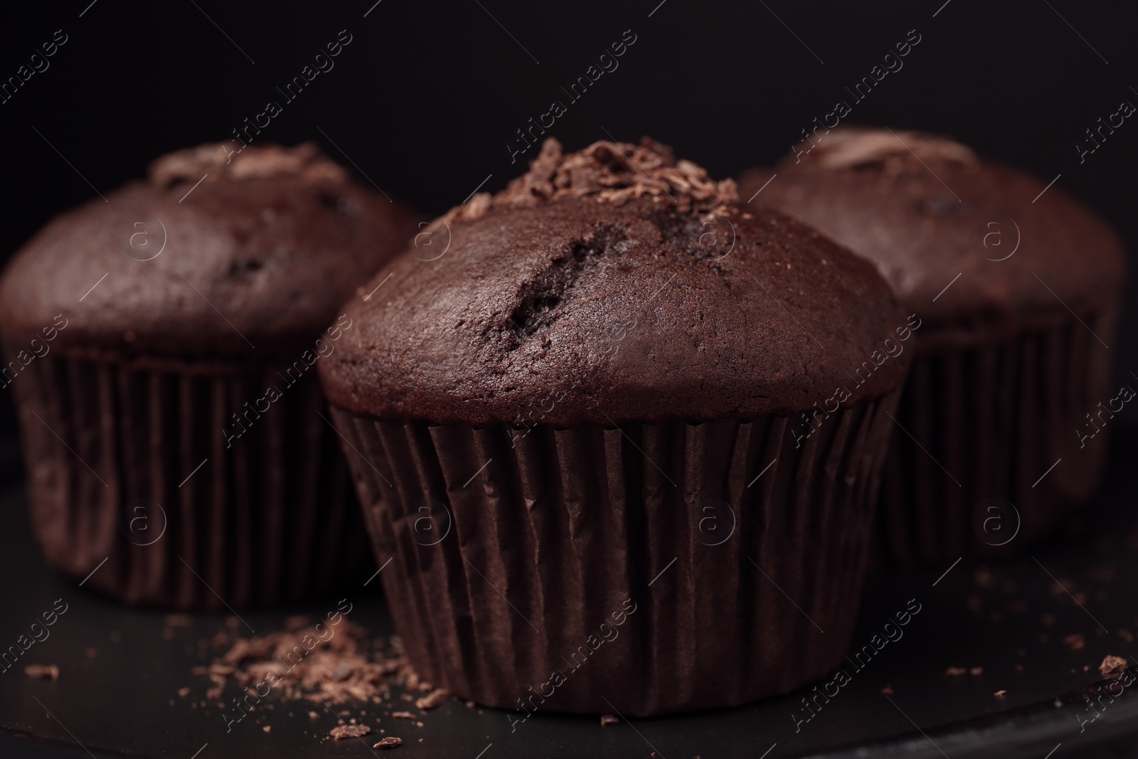 Photo of Delicious cupcakes with chocolate crumbles on black table, closeup