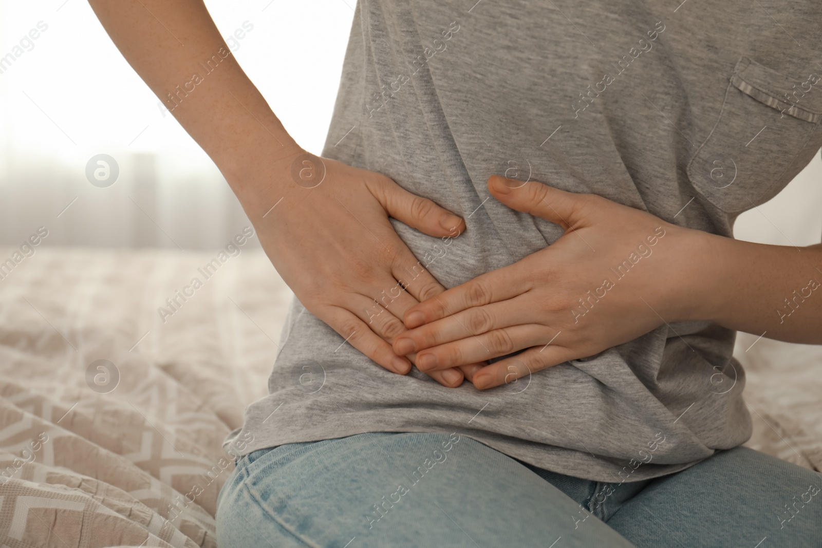 Photo of Woman suffering from appendicitis inflammation on bed at home, closeup