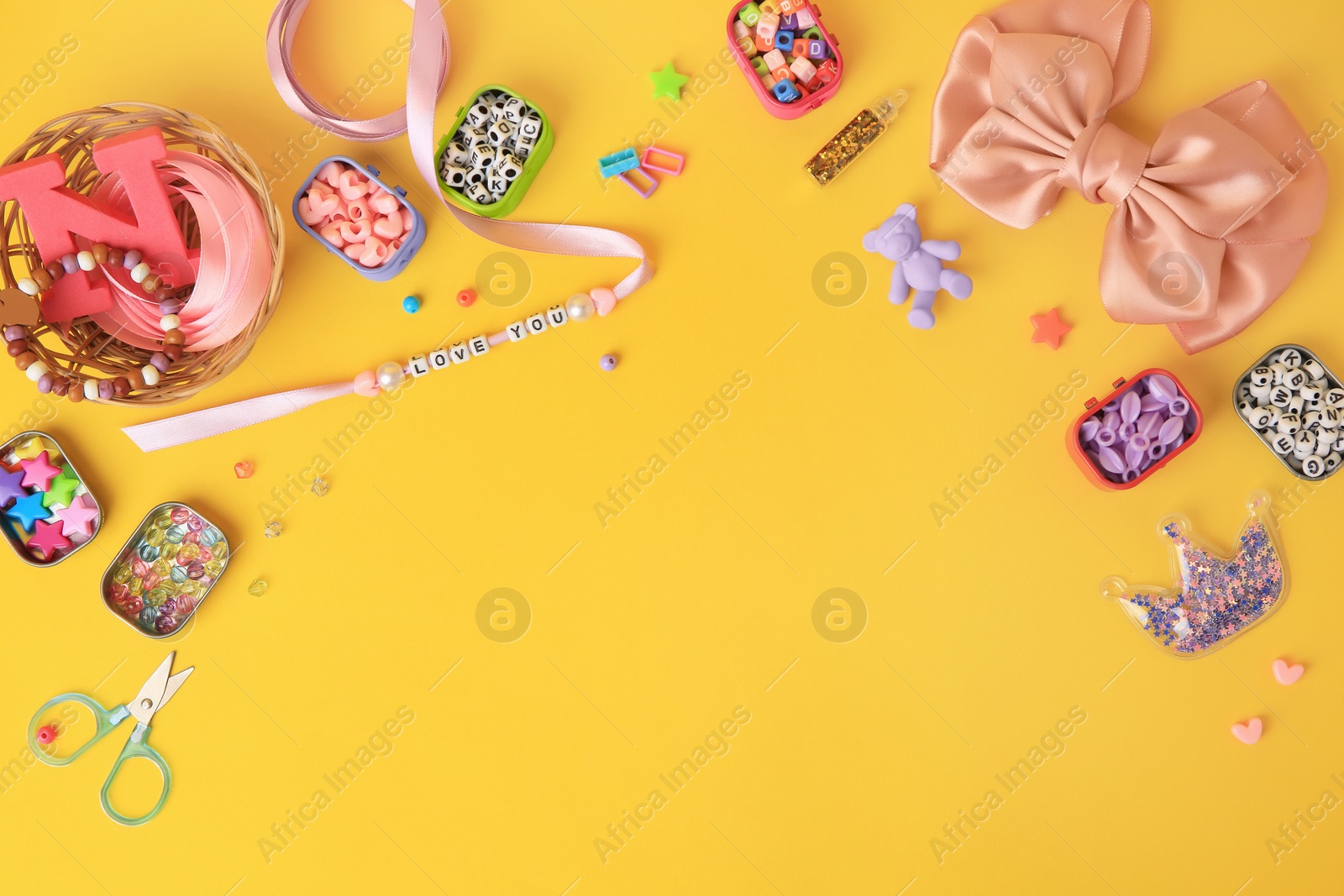 Photo of Kid`s handmade jewelry kit. Colorful beads, ribbon, bow and different supplies on orange background, flat lay. Space for text