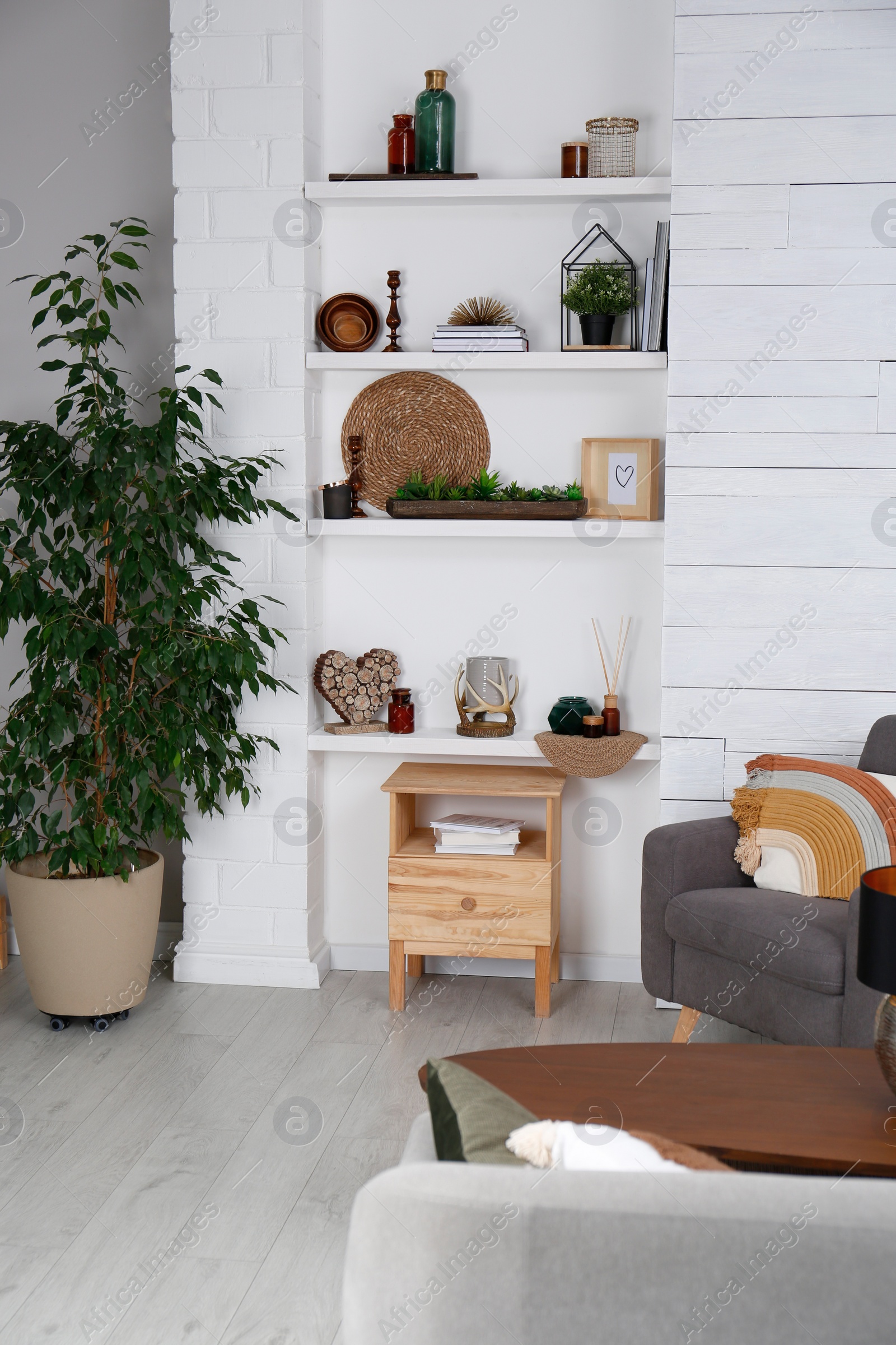 Photo of Stylish living room interior with comfortable armchair, wall shelves and beautiful decor elements