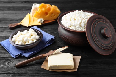 Photo of Clay dishware with fresh dairy products on black wooden table