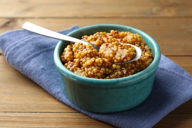 Photo of Whole grain mustard in bowl and spoon on wooden table