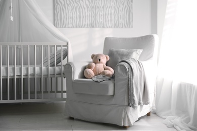 Photo of Baby room interior with comfortable crib and armchair