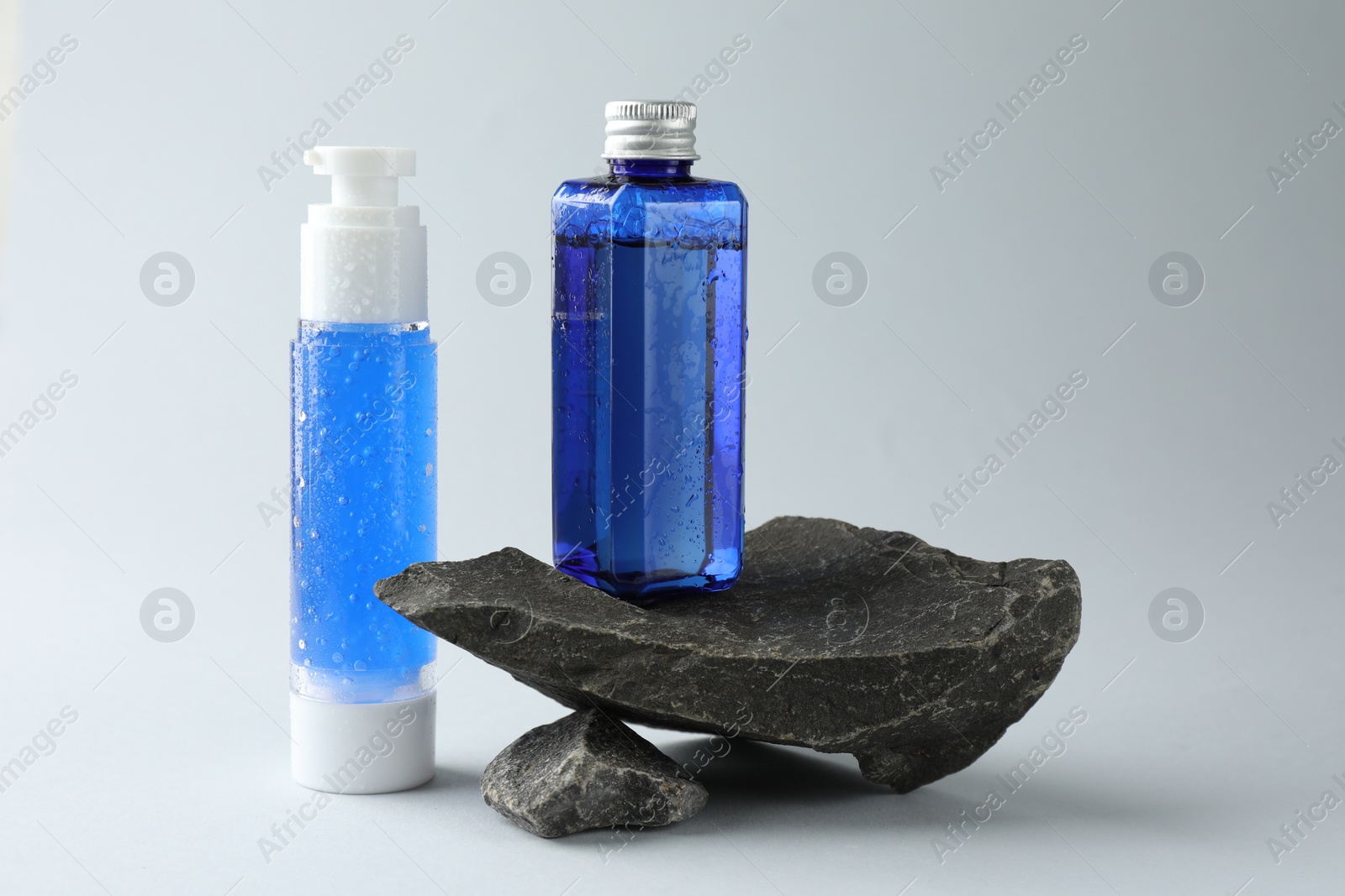 Photo of Bottles of cosmetic products on light grey background