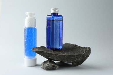 Bottles of cosmetic products on light grey background