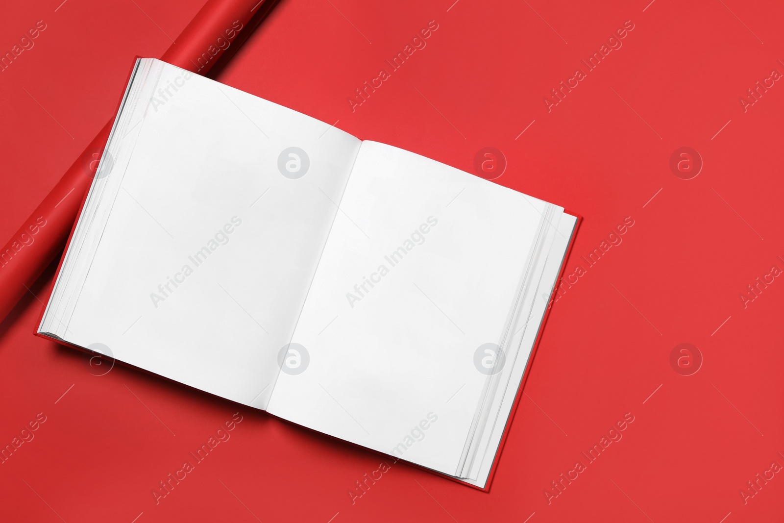 Photo of Open book with blank pages on red background, top view. Space for text