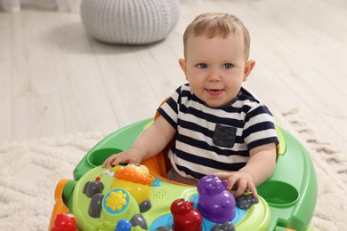 Portrait of cute baby with toy walker at home, space for text. Learning to walk