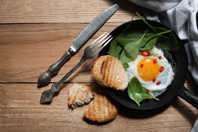 Delicious fried egg with spinach and chilli served on wooden table, flat lay