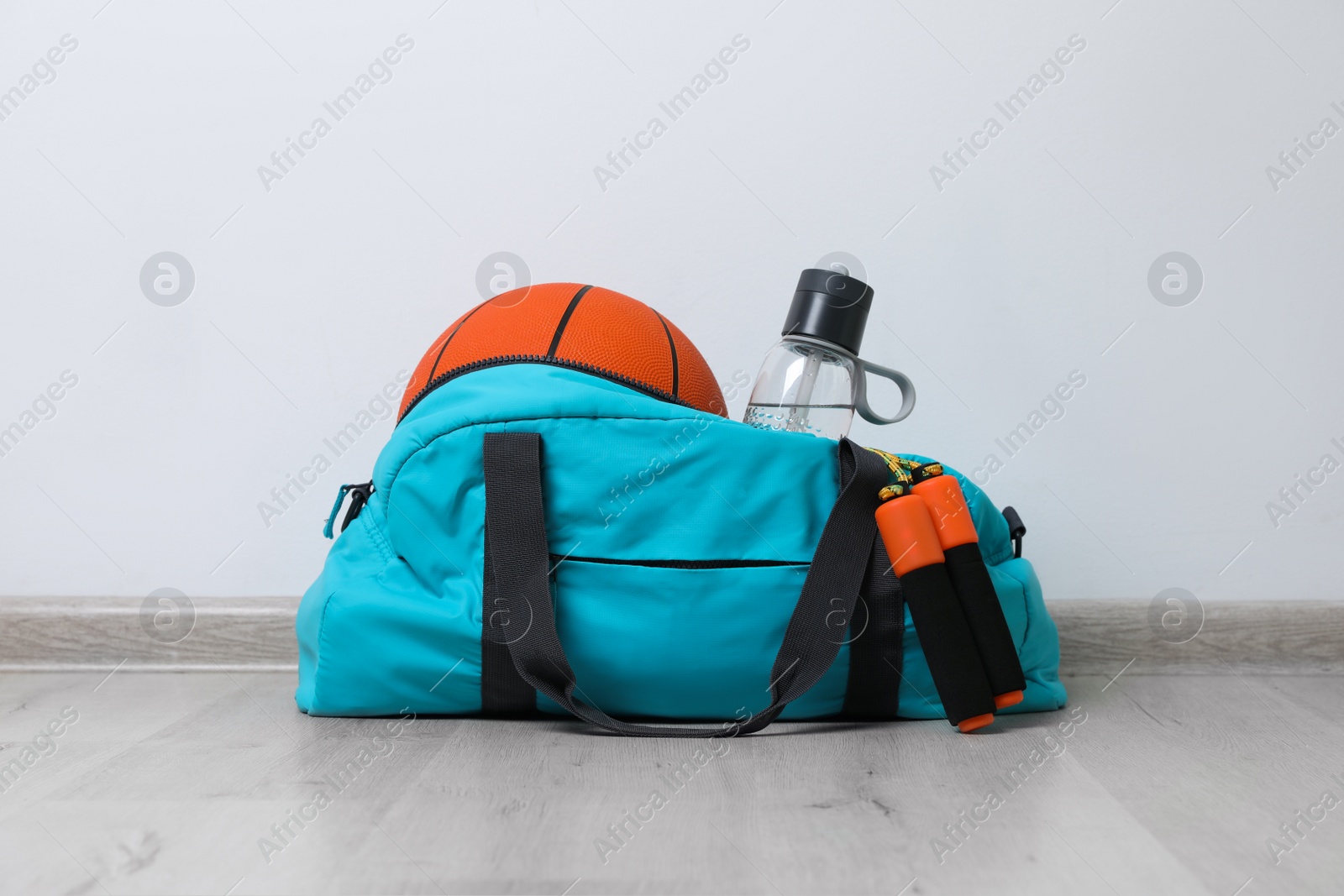 Photo of Stylish sports bag with different gym stuff on wooden floor indoors