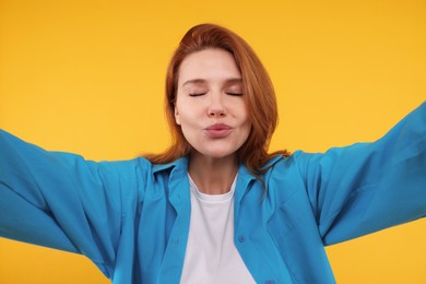 Beautiful woman taking selfie on orange background