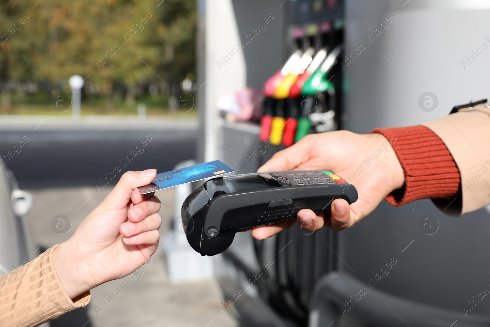 Photo of Woman sitting in car and paying with credit card at gas station, closeup