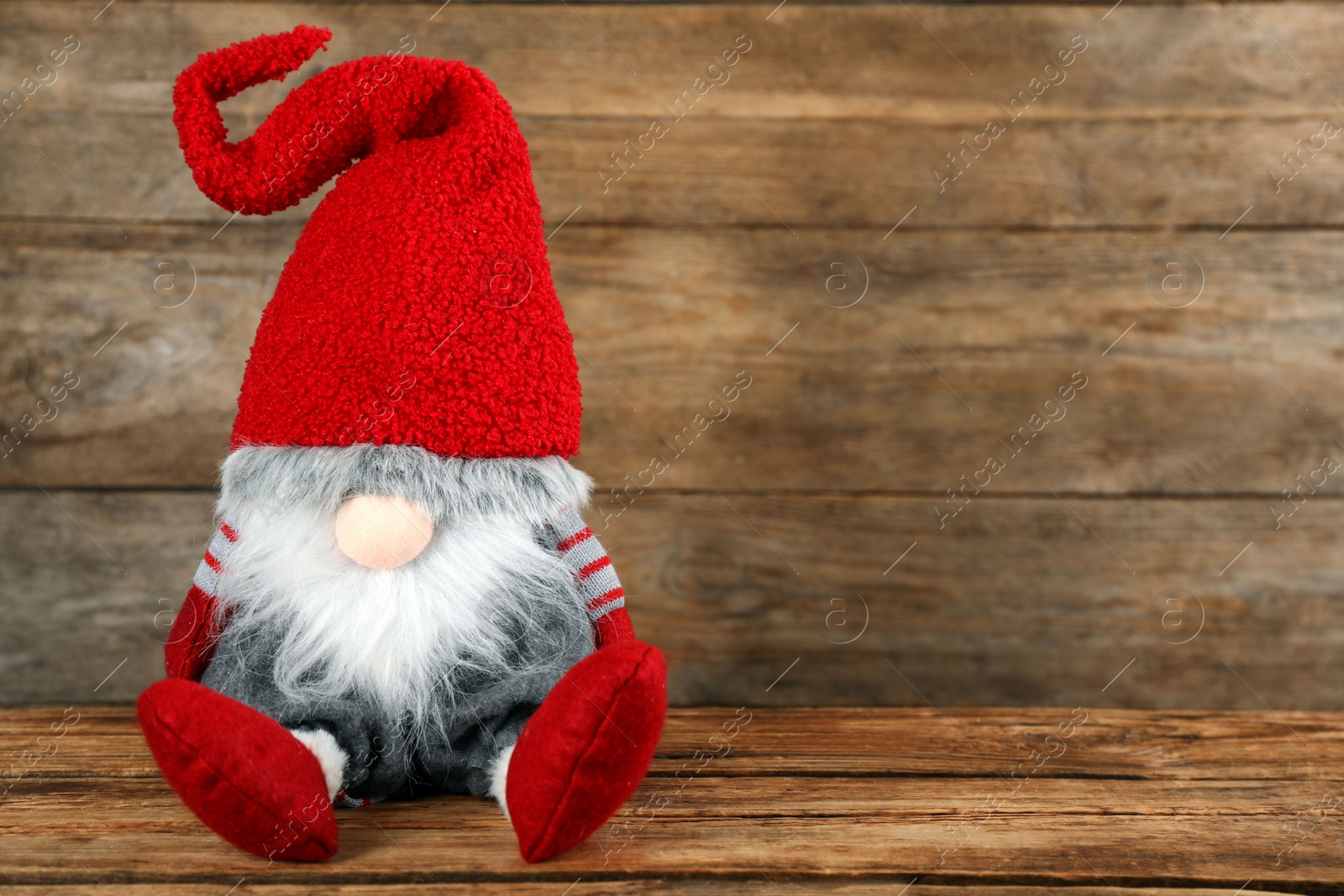 Photo of Cute Christmas gnome on wooden table. Space for text