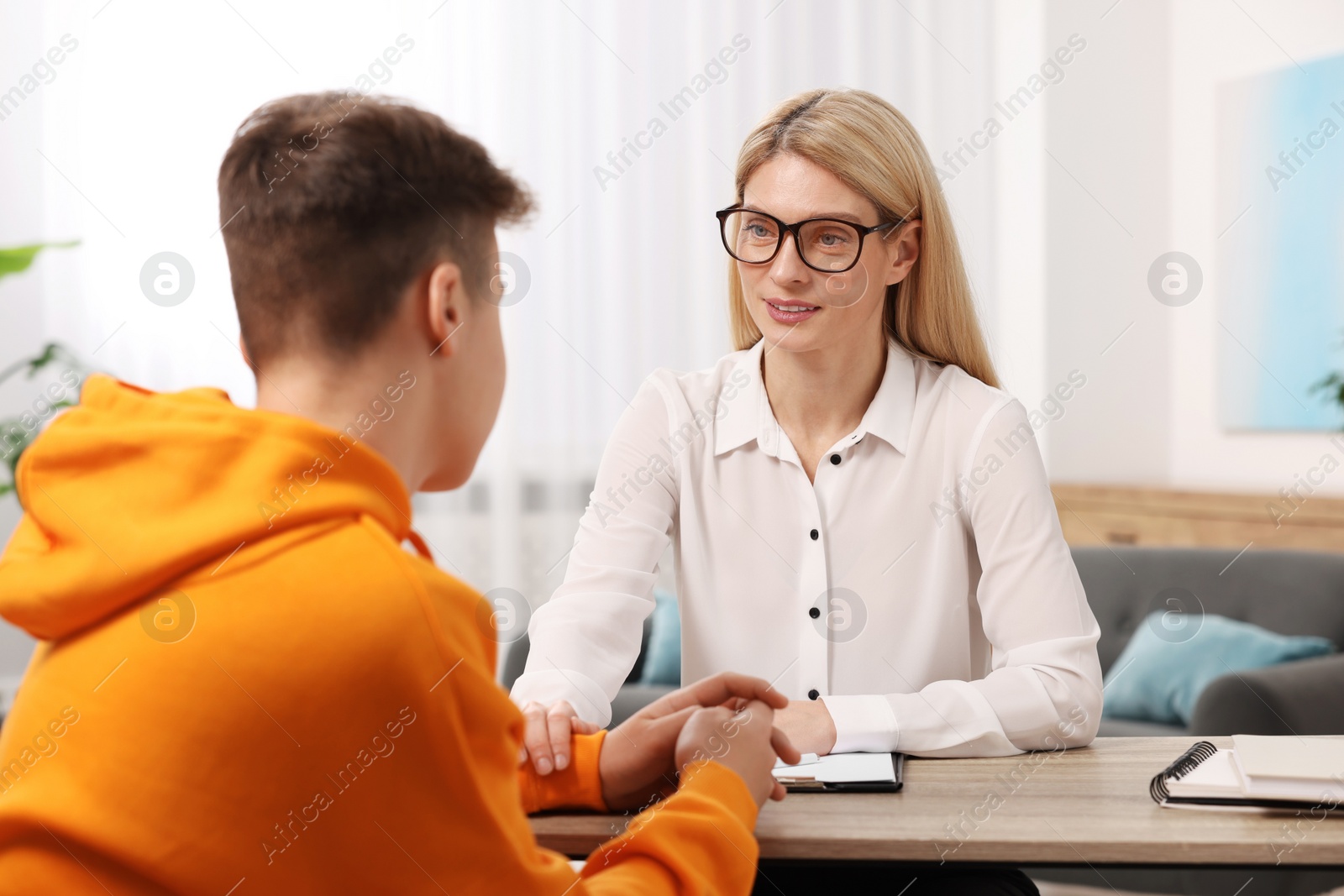 Photo of Psychologist working with teenage boy at table in office