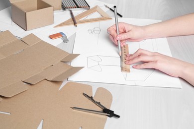 Photo of Woman creating packaging design at light wooden table, closeup