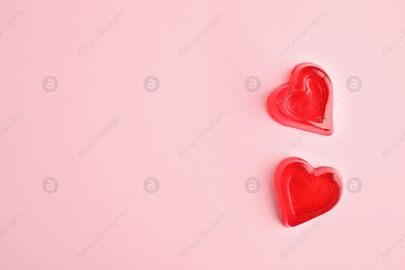 Photo of Tasty heart shaped jelly candies on pink background, flat lay. Space for text