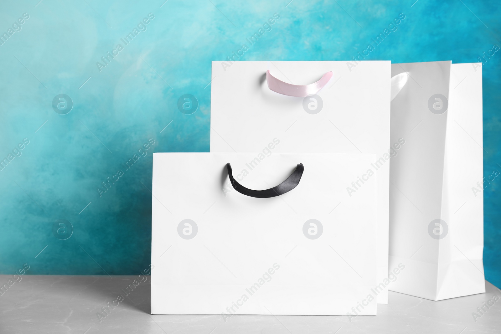 Photo of Paper shopping bags on table against color background. Mock up for design