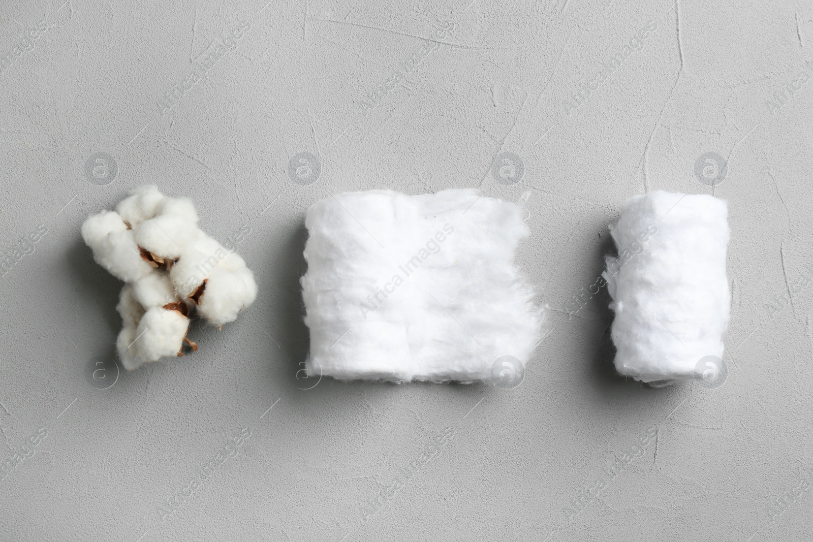 Photo of Flat lay composition with cotton rolls and flowers on grey stone background