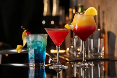 Photo of Different delicious cocktails on black table in bar