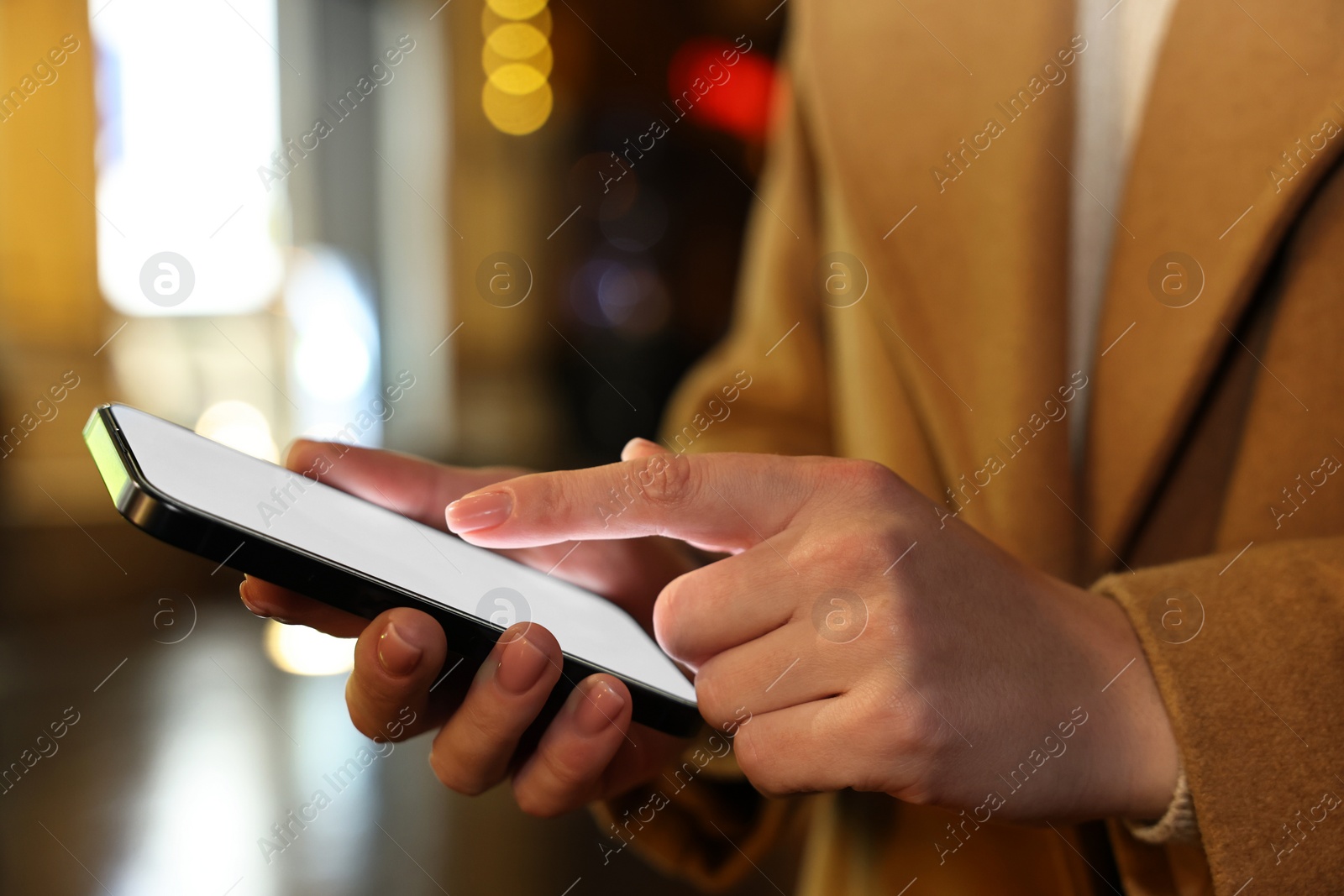 Photo of Woman using smartphone on night city street, closeup