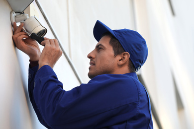 Photo of Technician installing CCTV camera on wall outdoors